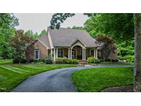 Beautiful brick home features a circular driveway, manicured lawn, and a covered front porch with stately columns at 3197 Carriage Creek Ct, Haw River, NC 27258