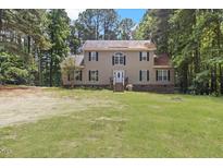 Charming two-story home with a well-maintained lawn and a welcoming front porch and set among many trees at 3841 Rawls Church Rd, Fuquay Varina, NC 27526