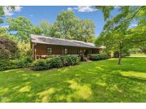 Inviting backyard featuring lush green grass, mature trees, and a charming home exterior with a wooden deck, perfect for outdoor living at 6971 Shady Creek Trl, Rougemont, NC 27572