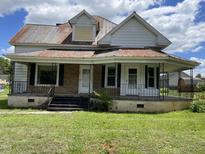 Charming home with a covered front porch, black iron railings, and a spacious front lawn at 705 Washington St, Graham, NC 27253