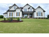 Stunning two-story home with light siding, brown shutters, manicured lawn and attractive landscaping at 90 Water Willow Ln, Zebulon, NC 27597