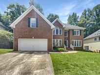 Charming two-story brick home with a well-manicured lawn, an attached two-car garage, and beautiful green window shutters at 105 Crosswaite Way, Cary, NC 27518