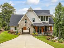 Elegant home featuring stone accents, a porte-cochere, a covered porch, and professional landscaping at 121 Anfield Rd, New Hill, NC 27562