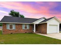 Charming brick home with a well-maintained lawn and attached garage offers curb appeal at 1602 Fairground Rd, Dunn, NC 28334