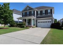 Charming two-story home with a manicured lawn, two car garage, and a welcoming light blue front door at 2309 Redbridge Ln, Apex, NC 27502