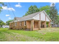 Ranch-style home featuring brick exterior, covered front porch, and established landscaping at 310 Wood St, Gibsonville, NC 27249