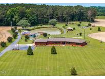 Expansive estate featuring a charming brick home, serene pond, and lush landscaping from an elevated perspective at 3187 Wilsons Mills Rd, Smithfield, NC 27577