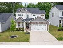 Charming two-story home featuring a manicured lawn, stone accents, and a spacious two-car garage at 389 Whetstone Dr, Angier, NC 27501