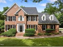 Traditional brick home featuring black shutters, dormer windows, and a professionally landscaped front yard at 100 Silver Lining Ln, Cary, NC 27513