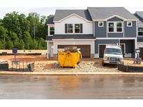Two-story townhome exterior during construction, featuring a visible dumpster, construction equipment, and landscaping materials at 1027 Winding Spring Dr, Mebane, NC 27302