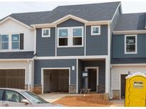 Modern townhome featuring blue siding, stone accents, open garage and covered front entry at 1029 Winding Spring Dr, Mebane, NC 27302