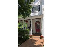 Inviting front porch with red door, swing chairs, and decorative flower baskets for a welcoming entrance at 104 Edgewater Cir, Chapel Hill, NC 27516