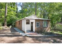 Charming brick home featuring white trim, a cozy front porch, and mature trees in a tranquil, wooded setting at 126 Barclay Rd, Chapel Hill, NC 27516