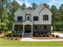 Stunning two-story home with a combination of stone and white wood and a welcoming front porch at 1338 The Parks Dr, Pittsboro, NC 27312