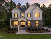 Stunning two-story home with stone accents, white siding, covered porch, and manicured lawn at 1338 The Parks Dr, Pittsboro, NC 27312