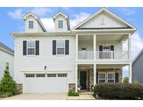 Charming two-story home featuring a welcoming front porch, a two car garage, and manicured landscaping at 145 Cassada Ct, Holly Springs, NC 27540