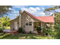 Charming home featuring a durable red metal roof, deck and well-maintained lawn at 1908 Rocky Cross Rd, Zebulon, NC 27597