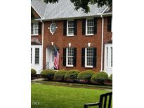 Charming brick townhouse featuring an arched entrance, black shutters, and a well-manicured lawn at 227 Kenmont Dr, Holly Springs, NC 27540