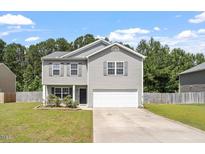 Charming two-story home featuring gray siding, a well-manicured lawn, and an attached garage at 228 Botanical Ct, Bunnlevel, NC 28323