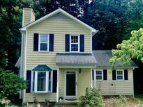 Charming two-story home featuring a yellow exterior, dark shutters, and a well-maintained front yard at 4009 Olde Coach Rd, Durham, NC 27707