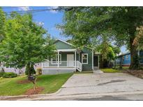 Charming green home featuring a cozy front porch with white railing and a well-manicured lawn at 507 N Elm St, Durham, NC 27701