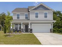 Charming two-story home with light gray siding, stone accents and a two-car garage at 516 Winding Creek Dr, Lillington, NC 27546