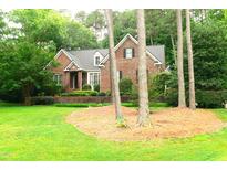 Charming brick home featuring lush green lawn, mature trees, and beautiful landscaping at 5401 Fire Pink Way, Raleigh, NC 27613
