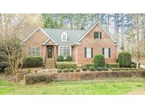 Charming brick home featuring a well-manicured lawn, mature trees, and a welcoming entrance at 5401 Fire Pink Way, Raleigh, NC 27613