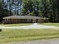 Brick home featuring a well-kept lawn, mature trees and shrubs, set beneath a bright blue sky at 106 N Lakeside Dr, Smithfield, NC 27577