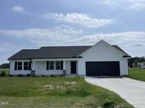 Charming single-story home featuring a black garage door and a well-maintained front lawn at 110 Coharie Dr, Lillington, NC 27546