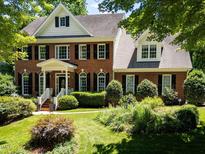 Beautiful brick home featuring a manicured lawn, black shutters, and mature landscaping, creating great curb appeal at 121 Flint Point Ln, Holly Springs, NC 27540