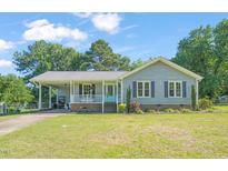Charming single story home with a covered front porch, blue shutters, and a well-maintained front lawn at 1413 Roy Averette Dr, Raleigh, NC 27603