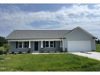 Charming single-story home with gray siding, manicured lawn, and attached two-car garage at 148 Coharie Dr, Lillington, NC 27546