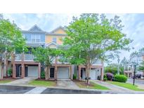 Townhome exterior featuring a brick facade, individual garages, and covered porches at 151 Braeside Ct, Cary, NC 27519