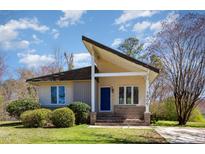 Charming single-story home featuring a unique roofline, blue front door, and lush landscaping at 1809 Coltrane Ct, Raleigh, NC 27610