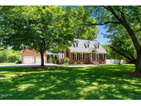 Charming brick home with a manicured lawn and mature trees for plenty of shade and a detached two-car garage at 2417 Ridgeford Ct, Fuquay Varina, NC 27526
