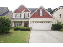 Traditional two-story home with a two-car garage, manicured lawn, and charming landscaping at 309 Forest Haven Drive Dr, Holly Springs, NC 27540