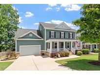 Charming two-story home with a welcoming front porch, landscaped yard, and attached garage provides curb appeal at 309 Larkhaven Pl, Apex, NC 27539