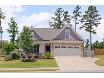 Charming home featuring stone accents, a gray two-car garage, an American flag, and a beautifully landscaped front yard at 40 Bourne Dr, Franklinton, NC 27525
