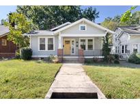 Charming single-story home featuring a quaint front porch, bright yellow door, and beautifully maintained yard at 409 N Hyde Park Ave, Durham, NC 27703