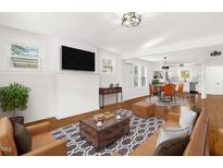 Open concept living room with hardwood floors, TV, stylish furniture and views to the kitchen at 507 Price Ave, Durham, NC 27701