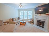 Cozy living room with fireplace, plush seating, and bright natural light from large windows at 5113 Lady Of The Lake Dr, Raleigh, NC 27612