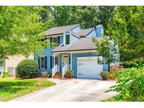 Charming two-story home with a blue exterior, well-manicured lawn, and attached garage in a lush, green neighborhood at 6104 New Market Way, Raleigh, NC 27609