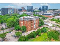 Stunning aerial view of a red brick apartment building with cityscape backdrop and mature landscaping at 710 Independence Pl # 301, Raleigh, NC 27603
