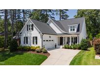 Charming white home with a black roof, lush landscaping, and an attached garage at 911 Canterbury Rd, Raleigh, NC 27607
