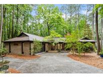 Charming brick home with mature trees, lush landscaping, and a paved driveway creating a welcoming curb appeal at 109 Loch Haven Ln, Cary, NC 27518
