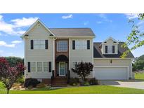 Inviting two-story home featuring a well-manicured lawn and attached two-car garage, creating perfect curb appeal at 115 Spring Branch Dr, Four Oaks, NC 27524