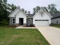 Charming home with white vertical siding, stone accents, a two-car garage, and a well-manicured lawn at 146 Wabash St, Pittsboro, NC 27312