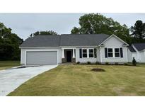 Charming single-story home with a gray exterior, manicured lawn, and attached garage offers modern curb appeal at 151 Oakfield Trace Dr, Four Oaks, NC 27524