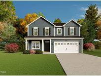 Charming two-story home with a well-manicured lawn and a two-car garage, set against a backdrop of lush trees at 173 Jones Creek Ln, Lillington, NC 27546